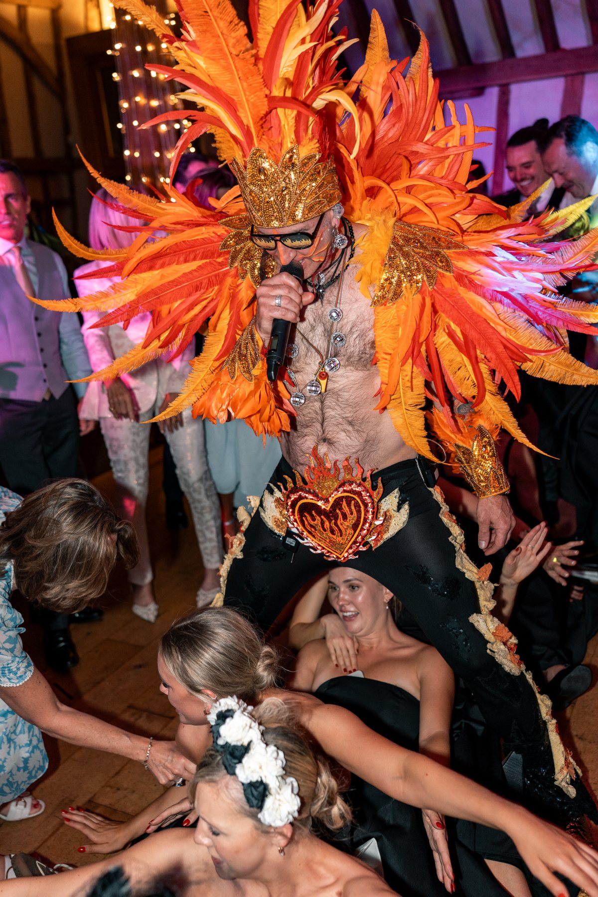 The frontman leaning over laughing guests as they reach up from the barn floor