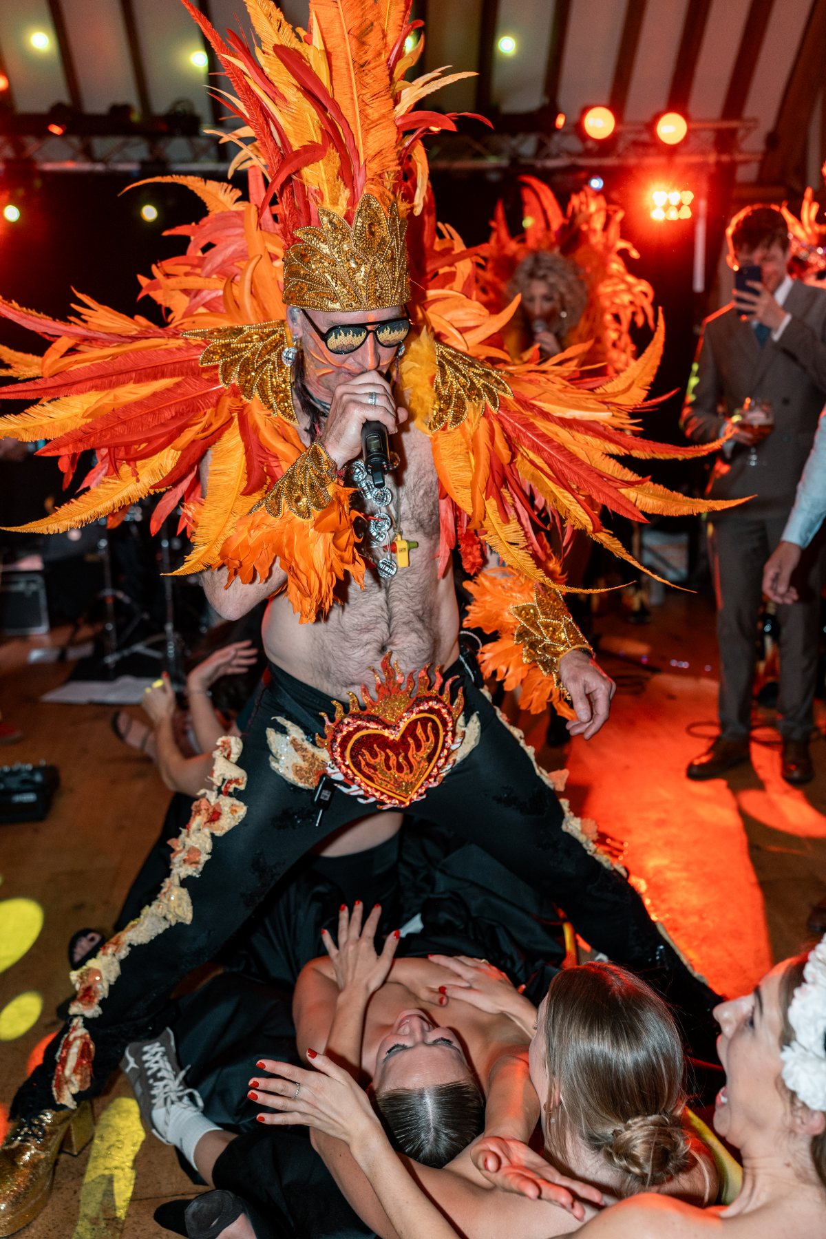 Guests on the floor reaching up to the frontman as he leans over them, a mirror ball catching the light behind
