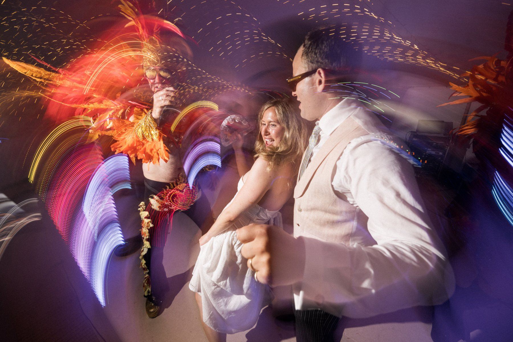 Couple dancing together as the frontman sings beside them, coloured light trails streaking across the frame